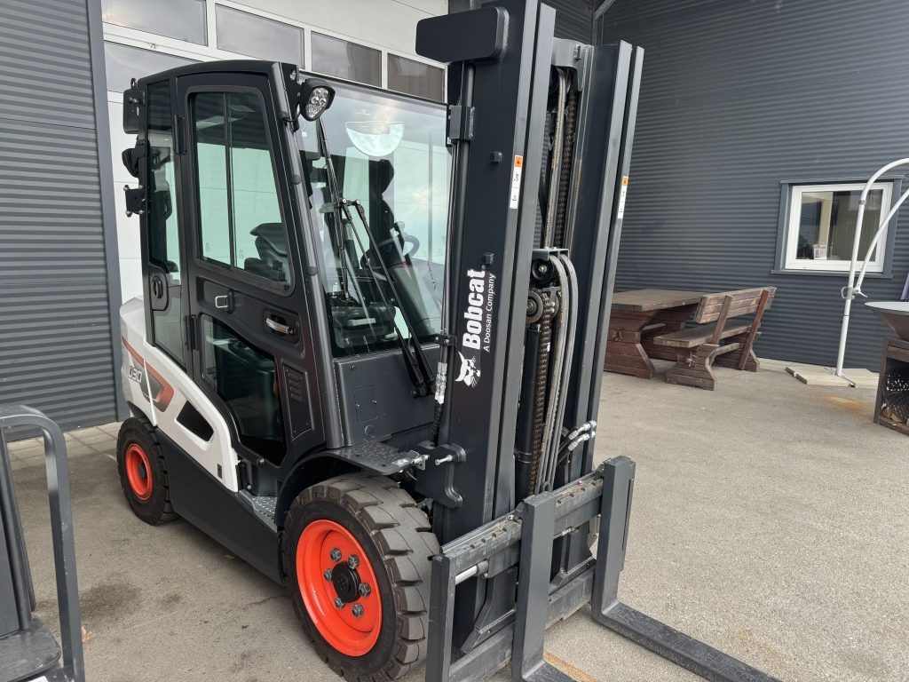 Bobcat Stapler mit Kabine vor dunkler Halle