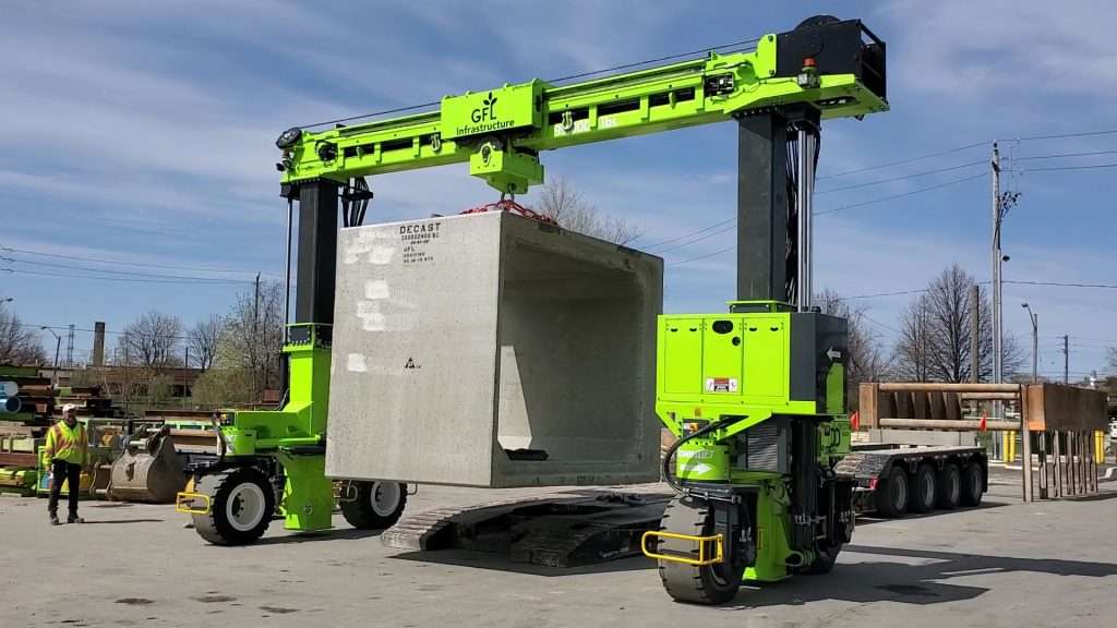 Gruener Portalstapler hebt Betonblock von Sattelauflieger