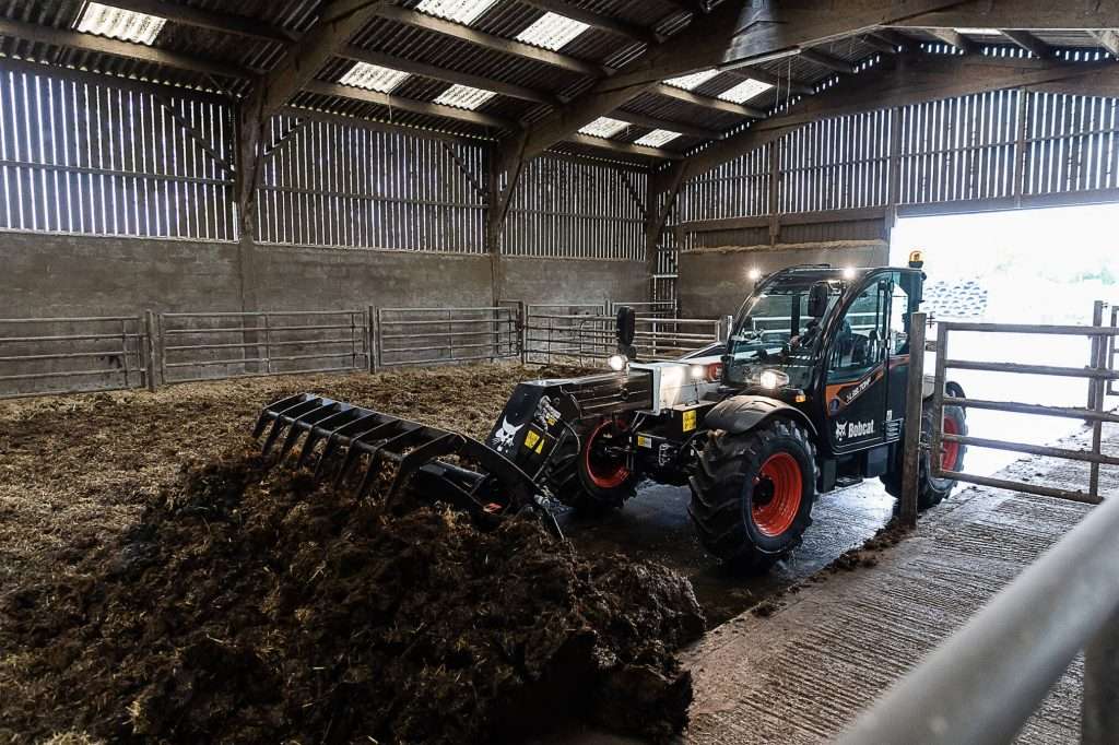 Bobcat Teleskoplader mit Greiferschaufel im Stall