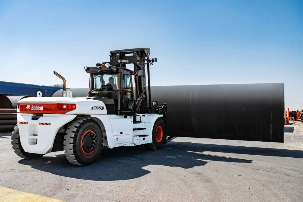 Schwerer Bobcat Stapler transportiert riesiges Stahlrohr