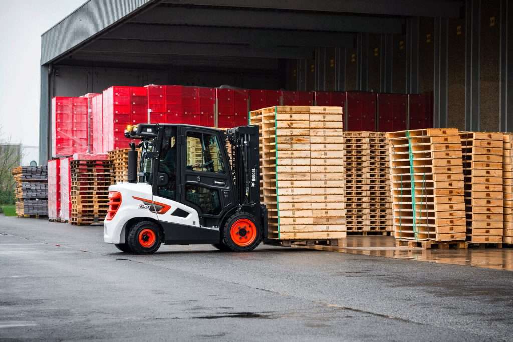 Bobcat Stapler vor Hallentor mit gestapelten Paletten