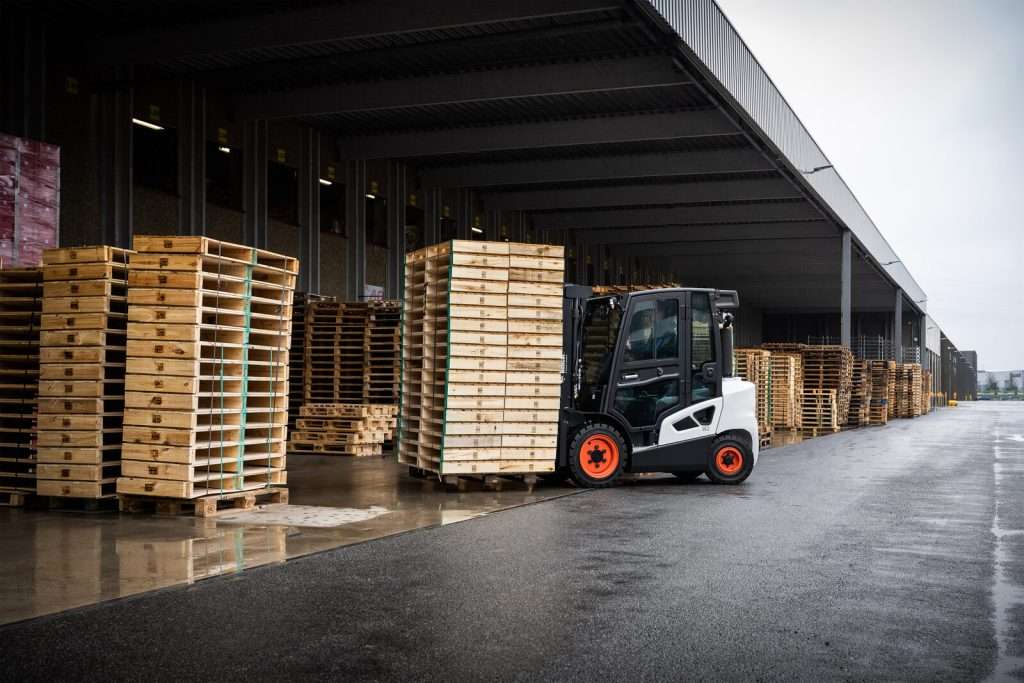 Bobcat Stapler weit hinten in Verladehalle mit Palettenstapeln