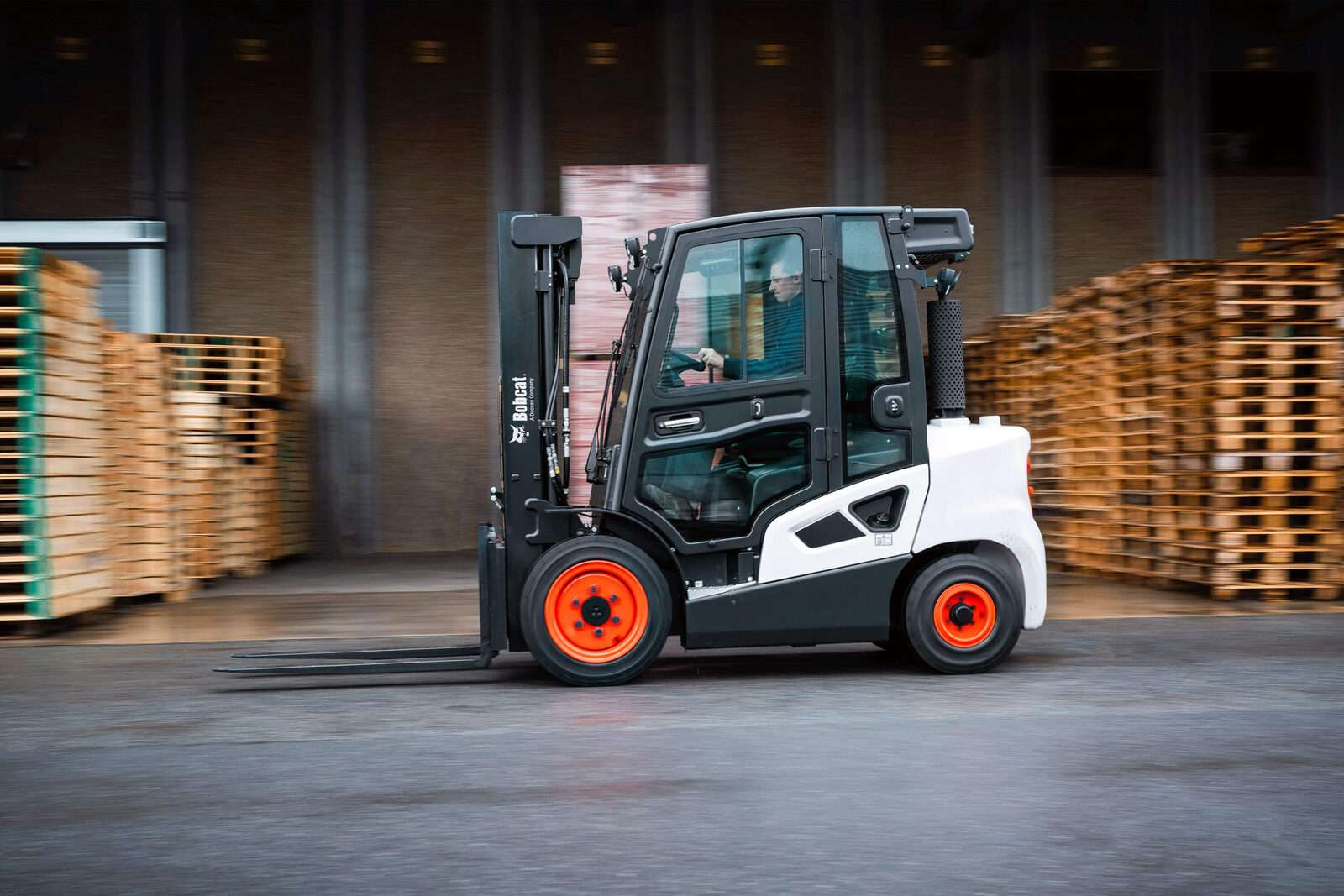 Bobcat Stapler mit Kabine seitlich vor Palettenstapeln