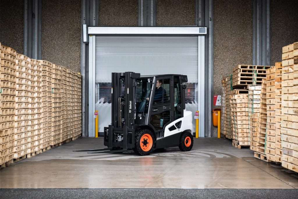 Bobcat Stapler am Hallentor zwischen Palettenstapeln