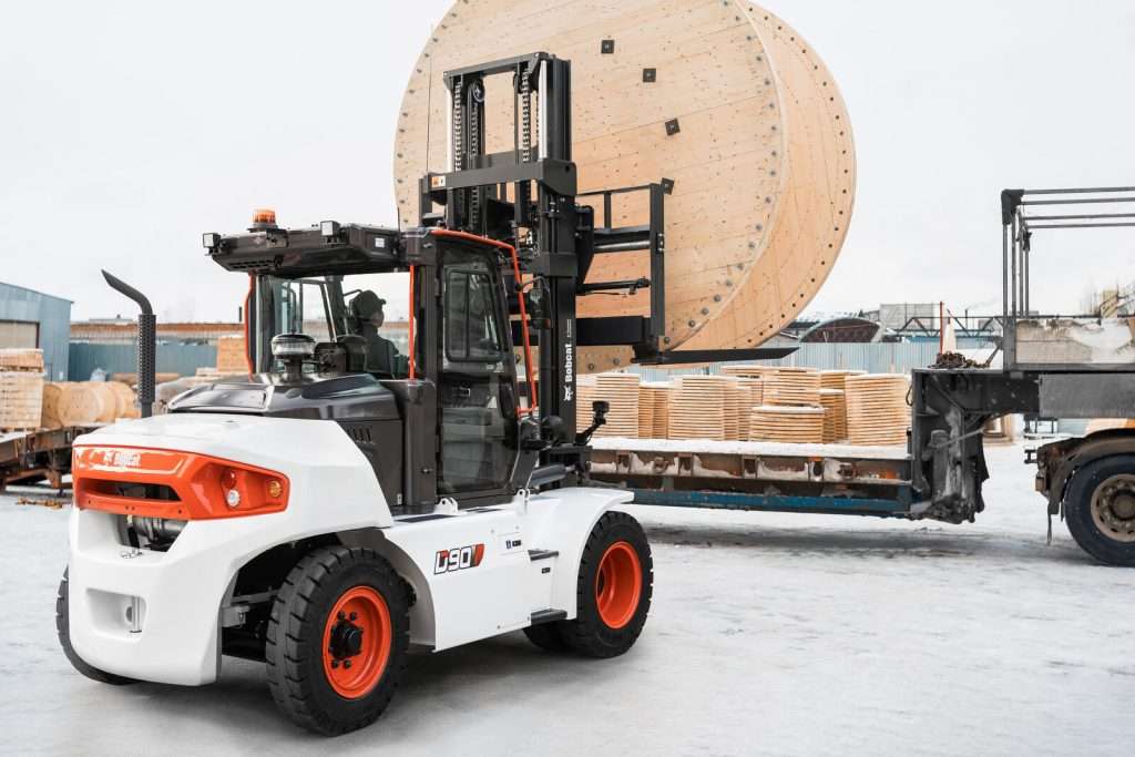 Stapler hebt Kabeltrommel im Schnee auf Lkw-Ladeflaeche