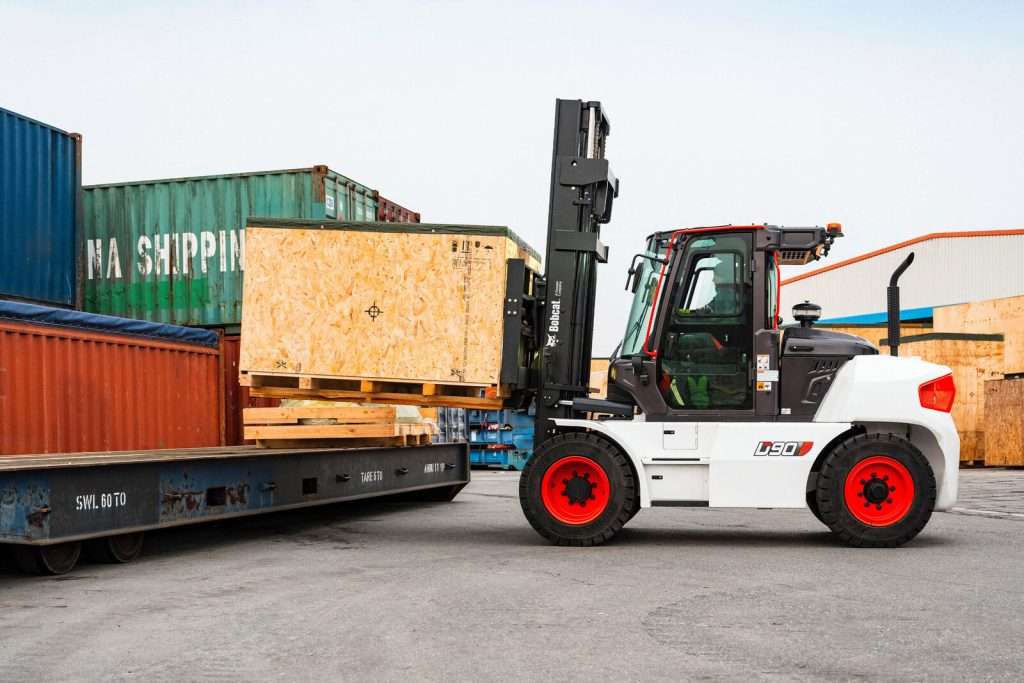 Bobcat Schwerlaststapler verlaedt Holzkiste auf Container Auflieger