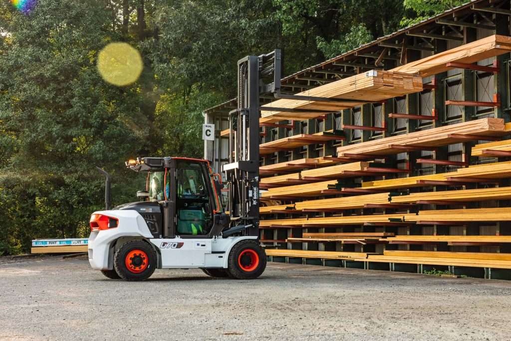 Bobcat Stapler vor Kragarmregal mit Schnittholz im Gegenlicht
