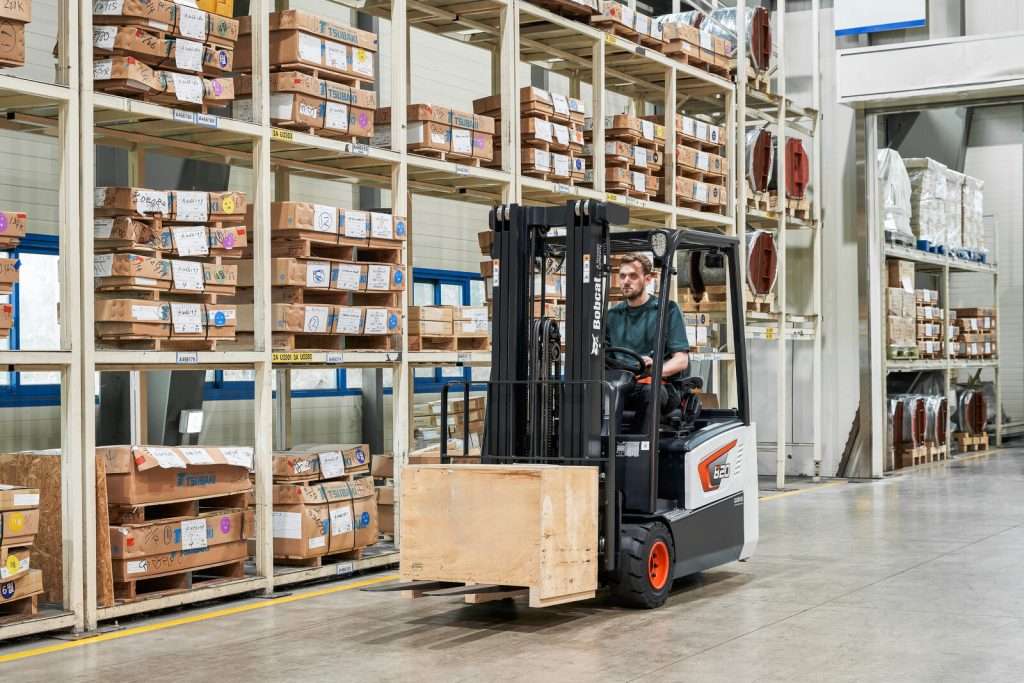 Bobcat Elektrostapler transportiert Holzkiste im Lager