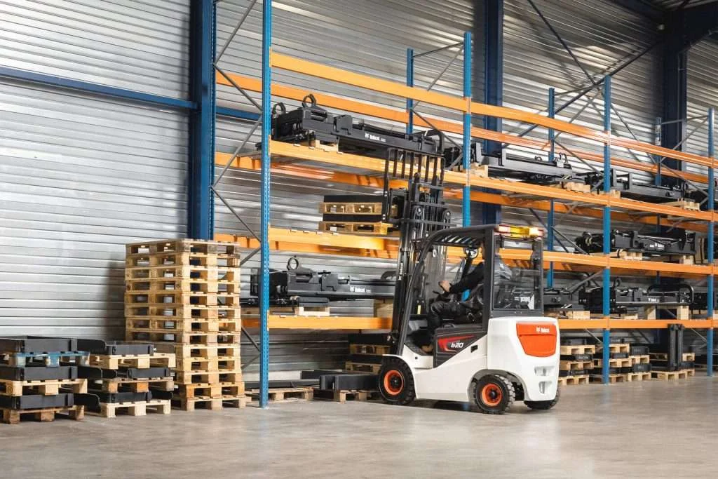 Bobcat Elektrostapler faehrt im Regallager an Paletten vorbei