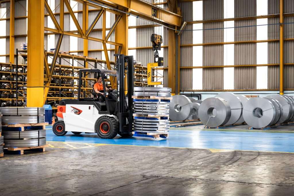 Bobcat Elektrostapler zwischen Stahlcoils in Produktionshalle