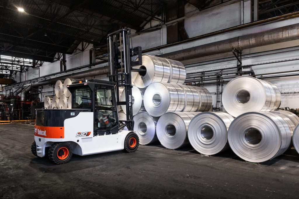 Bobcat Stapler vor Aluminium-Coils in dunkler Halle