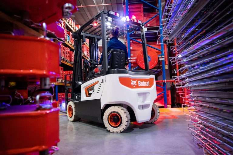 Bobcat Elektrostapler in Regalgasse mit buntem Licht