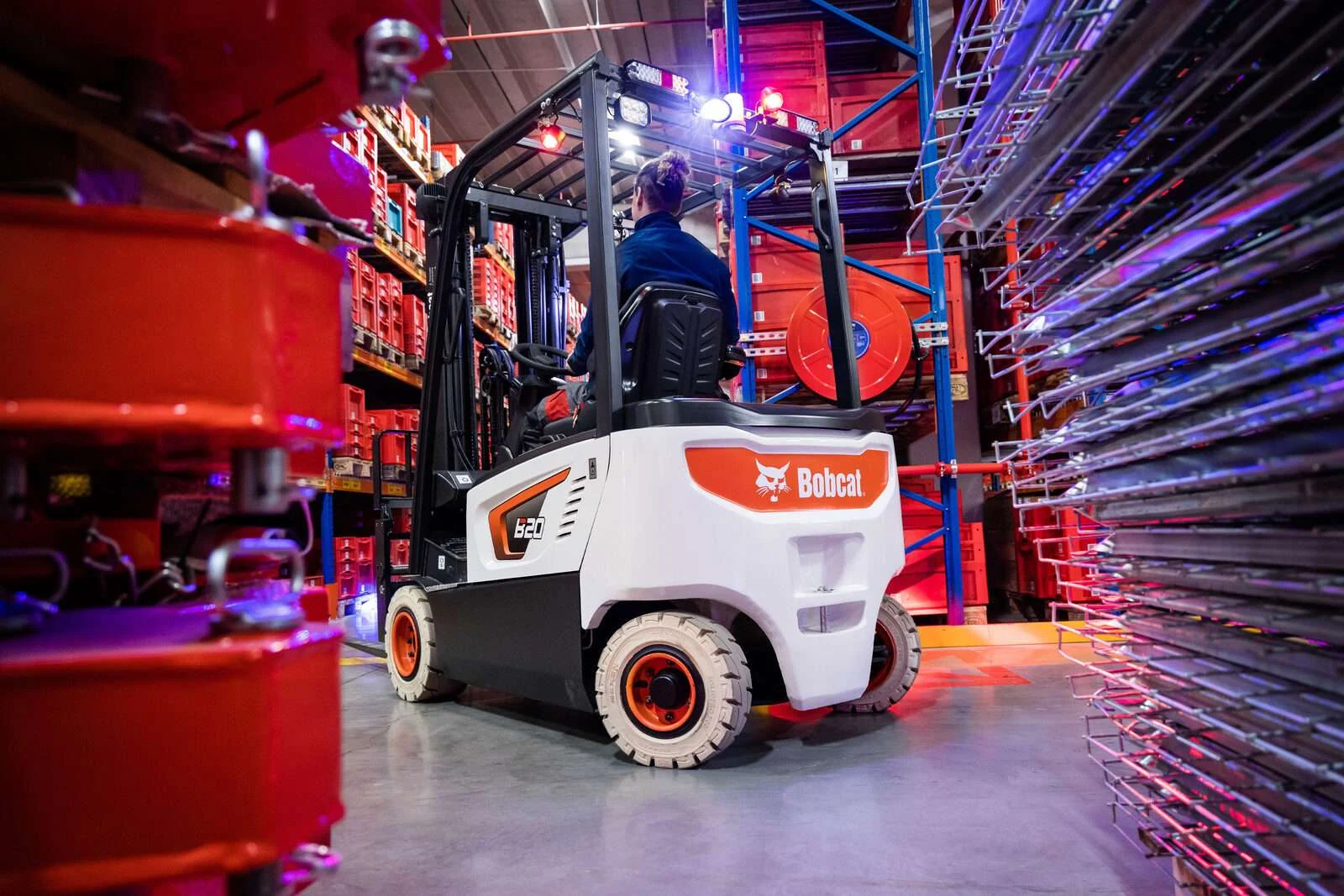 Bobcat Elektrostapler in Regalgasse mit buntem Licht