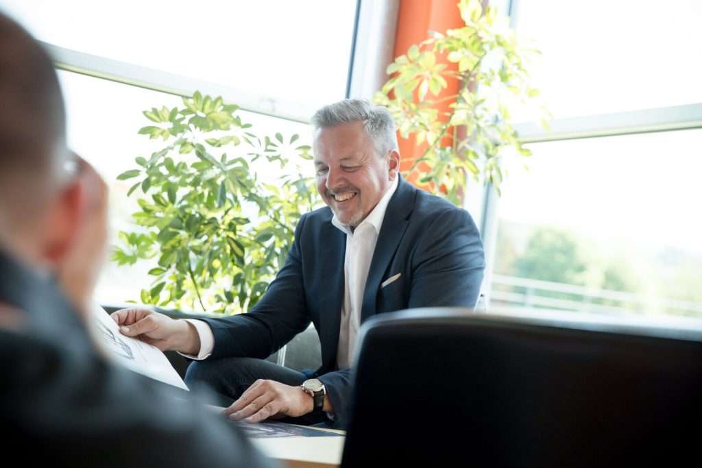 Verkaufsberater lacht beim Blick in Prospekt
