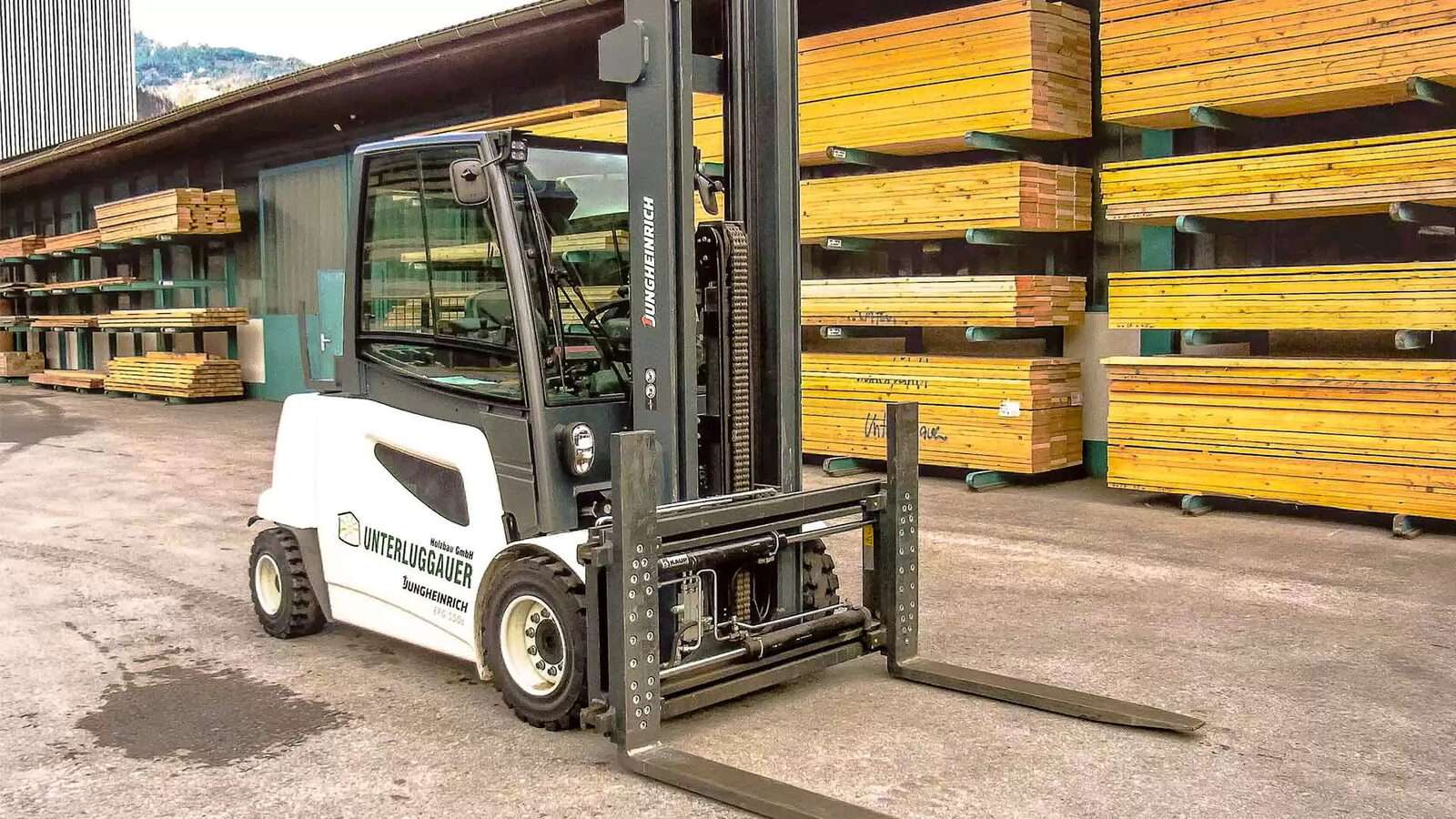 Elektrostapler mit Zinkenverstellgerät vor Holzlager