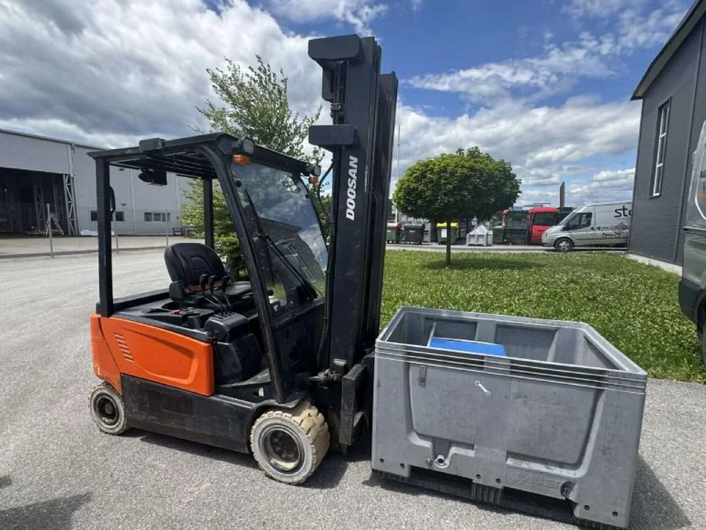 Doosan Elektrostapler neben Gitterbox auf Hof